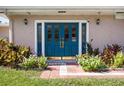 Close-up of a home's inviting blue double door entry with decorative sidelights and surrounding landscaping at 12757 Circle Lake Dr, Hudson, FL 34669