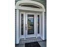 Close-up of a white front door featuring decorative glass and detailed trim at 5050 Limestone Dr, Port Richey, FL 34668