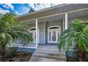 Close-up of the beautiful front entrance featuring a charming porch and tropical landscaping at 5050 Limestone Dr, Port Richey, FL 34668