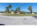 Scenic street view showcasing a well-maintained home with lush green lawns and swaying palm trees under a clear blue sky at 5061 Ensign Loop, New Port Richey, FL 34652