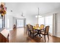 Well-lit dining room with hardwood floors, a modern chandelier, large windows, and a view of the front yard at 5903 War Admiral Dr, Wesley Chapel, FL 33544