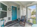 Cozy porch with a rocking chair, vibrant blue door, and ample natural light streaming through the screened windows at 610 Cobia Way, Oldsmar, FL 34677