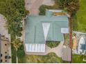 Aerial view of a home with a green roof, fenced yard, boat parking, and surrounding greenery at 646 Riverside Dr, Tarpon Springs, FL 34689