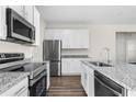Modern kitchen with stainless steel appliances, granite countertops, and white cabinets at 8983 Wade St, Brooksville, FL 34613