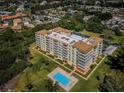 Aerial view of a tan condo complex surrounded by lush greenery and community pool at 9000 Commodore Dr # 302, Seminole, FL 33776