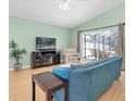 Bright living room featuring a plush blue sofa, light hardwood floors, and sliding glass doors to the screened lanai at 11700 Leda Ln, New Port Richey, FL 34654