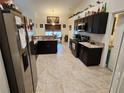 Bright, open kitchen with dark cabinets, stainless appliances, and expansive tile flooring at 12035 Ipswich Sparrow Rd, Weeki Wachee, FL 34614