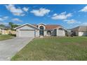 Charming single Gathering home features a 2-car garage and well-maintained lawn under a cloudy blue sky at 3606 Dow Ln, Spring Hill, FL 34609
