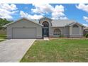 Charming single-story home with a well-manicured lawn, two car garage, and beautiful architectural details at 3606 Dow Ln, Spring Hill, FL 34609