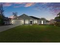 Charming home at twilight features a lush green lawn, two-car garage, and covered porch at 5139 Jenson Ave, Spring Hill, FL 34608