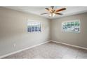Bedroom with light gray walls, tile floor, ceiling fan, and two windows providing natural light at 5345 Carlton Rd, New Port Richey, FL 34652