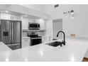 Bright kitchen featuring modern appliances, white cabinets, stainless steel fridge, and stylish countertops and backsplash at 1382 Aladdin Rd, Spring Hill, FL 34609