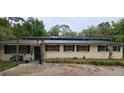 A single-story home with mature trees, a dark roof, and a large front yard at 17932 Wendy Sue Ave, Hudson, FL 34667