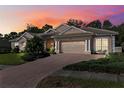 Beautiful home with a brick-paved driveway, manicured lawn, and a two-car garage during sunset at 5383 Firethorn Pt, Spring Hill, FL 34609