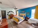 Bright main bedroom featuring wood-look floors, colorful accent wall, and access to the backyard at 5801 65Th N Ter, Pinellas Park, FL 33781
