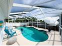 Inviting screened-in pool area featuring a unique kidney-shaped pool, patio furniture, and shade umbrella at 5801 65Th N Ter, Pinellas Park, FL 33781