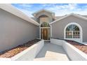 Close-up of the front entrance with a decorative wooden door, sidelights, and arched transom window at 14448 Linden Dr, Spring Hill, FL 34609