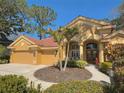 Lovely single-story home features a manicured circular garden and a tiled roof, surrounded by lush landscaping at 2806 Grey Oaks Blvd, Tarpon Springs, FL 34688