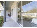 Covered back patio with glass sliding doors offers serene views of the white picket fence at 28752 Falling Leaves Way, Wesley Chapel, FL 33543