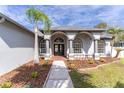 Inviting front entrance with a landscaped garden, arched columns, and double door entry at 28752 Falling Leaves Way, Wesley Chapel, FL 33543