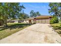 Street view of a one story residence with beautiful landscaping and an attached two-car garage at 3273 Bluestone Ave, Spring Hill, FL 34609