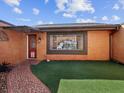 Close-up of home exterior featuring a faux grass yard, tiled walkway, and a window with security bars at 3730 Sail Dr, New Port Richey, FL 34652