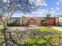 Charming single-story home featuring a lawn, arched entryway and an attached orange garage at 3730 Sail Dr, New Port Richey, FL 34652