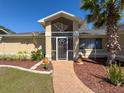 Close up on the front door with lush landscaping including a brick walkway and palm tree at 8173 Wysocki Ct, Spring Hill, FL 34606