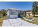 Charming waterfront home featuring a two-car garage, a basketball hoop, a well-manicured lawn, and lush landscaping at 8401 Carolyn Dr, Port Richey, FL 34668