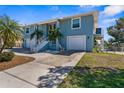 Charming home with two-car garage, white stairs leading to the entrance, and lush green lawn at 8408 Damen Ln, Port Richey, FL 34668