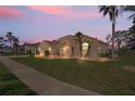 A single-story home with manicured lawn and palm trees at twilight at 14251 Mansfield Rd, Spring Hill, FL 34609