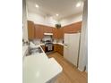 Bright kitchen showcases wood cabinets, an electric range, laminate floors and a white refrigerator at 2931 Walnut Grove Ct, Holiday, FL 34691