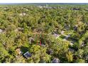 Aerial view of a house nestled among lush green trees in a quiet residential neighborhood at 406 Zoller St, Brooksville, FL 34601