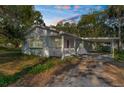 Single-story home with a covered carport and front porch surrounded by mature trees and greenery at 406 Zoller St, Brooksville, FL 34601