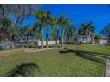 A green front yard with several palm trees offers a view of a charming house at 494 Village Dr, Tarpon Springs, FL 34689