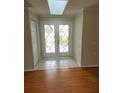 Bright foyer with double doors featuring decorative glass, tile floor, a skylight, and hardwood floors at 7106 Green Abbey Way, Spring Hill, FL 34606