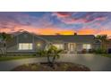 Charming single-story home with mature landscaping and a circular driveway, set against a vibrant sunset sky at 5000 Galleon Ct, New Port Richey, FL 34652