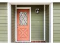 Close-up of a front door boasting a unique diamond-patterned window and a fresh coat of salmon paint at 5441 Alderwood St, Spring Hill, FL 34606