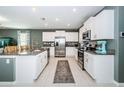 Bright kitchen boasts white cabinets, granite countertops, stainless steel appliances, and large center island at 6482 Beverly Hills Dr, Zephyrhills, FL 33541