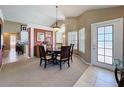 Traditional dining room with round table, carpet flooring, complemented by an elegant chandelier and outdoor access at 7912 Trail Run Loop, New Port Richey, FL 34653