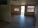 Open-concept living room featuring tile floors, neutral paint, and natural light from windows and a glass door at 12716 Mulberry Ln, Hudson, FL 34667