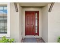 Inviting entryway featuring a red front door with sidelight window and stone pavers for a welcoming appeal at 4142 Montegrappa Way, Wesley Chapel, FL 33543