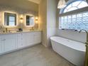 Luxurious bathroom featuring dual vanities, decorative mirrors and a soaking tub with modern fixtures at 6393 Pinehurst Dr, Spring Hill, FL 34606