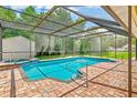 Screened in pool with jacuzzi and brick patio, surrounded by lush green grass and a shed at 8017 Shepherd Ave, Spring Hill, FL 34606