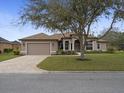 Well-maintained front exterior with a 2-car garage, brick driveway, and beautifully landscaped yard at 8373 Maybelle Dr, Weeki Wachee, FL 34613