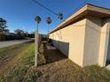 View of side yard with light colored exterior, wooden fence, grass, and palm trees in background at 8607 Longboat Ln, Hudson, FL 34667