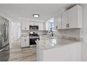 Bright kitchen featuring white cabinets, stainless steel appliances, gray backsplash, and sleek countertops at 10841 Scenic Dr, Port Richey, FL 34668