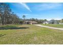Spacious front yard with well-maintained lawn and a charming single-story home with a three-car garage at 18251 East Rd, Hudson, FL 34667