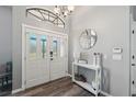 Welcoming foyer featuring decorative white doors with glass accents, a modern console table, and elegant lighting at 18251 East Rd, Hudson, FL 34667