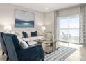 Bright living room features a plush white sofa, lake view, stylish decor, and sliding glass doors to the patio at 285 Voltaire Dr, Spring Hill, FL 34609